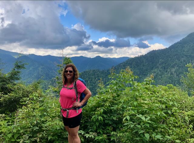 Lori at the Chimney Top Trail Overlook with a view of the Smoky Mountains from a distance. 