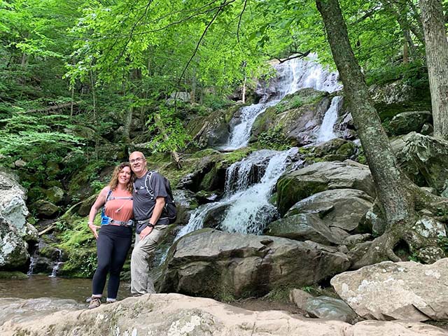 Lori and Steve are posing in front of Dark Hollow Falls. 