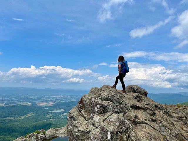 Lori Is standing at the peak of Little Stony Man trail and looking out at Page Valley