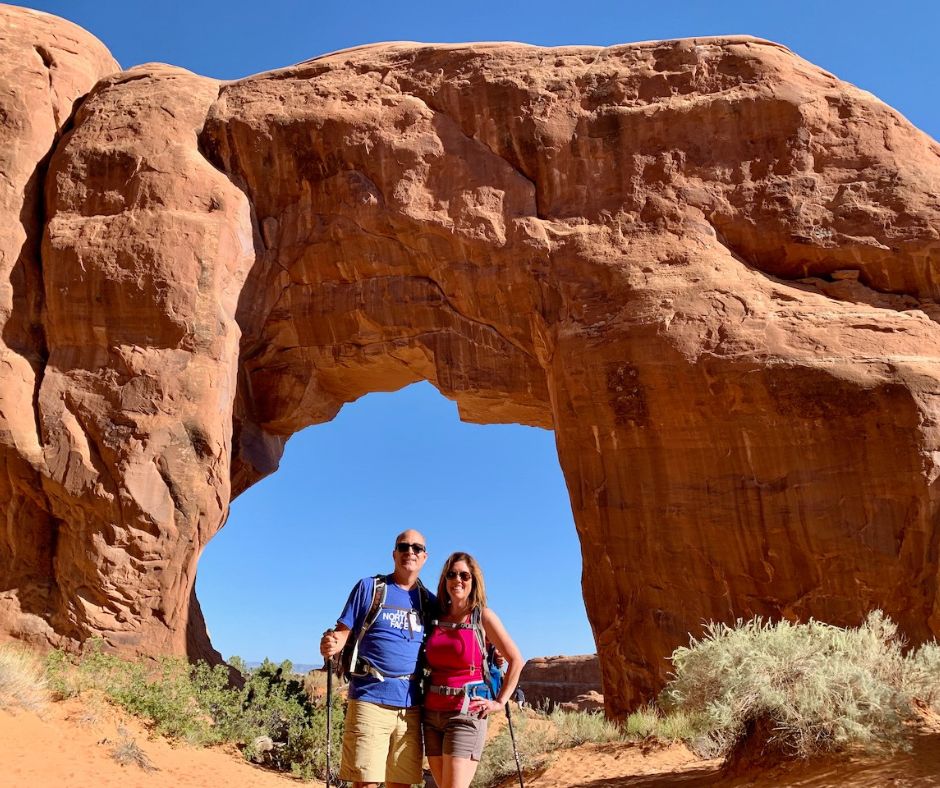 Lori and Steve are standing in front of Pine Tree Arch