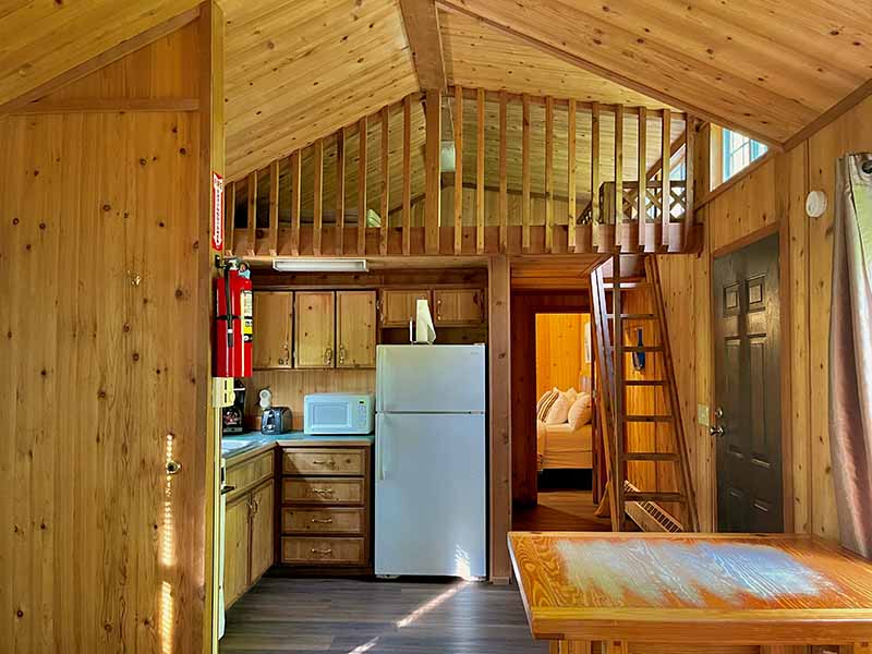 A inside view of and Ace White Adventure Resort Cabin showing the kitchen, a loft.  